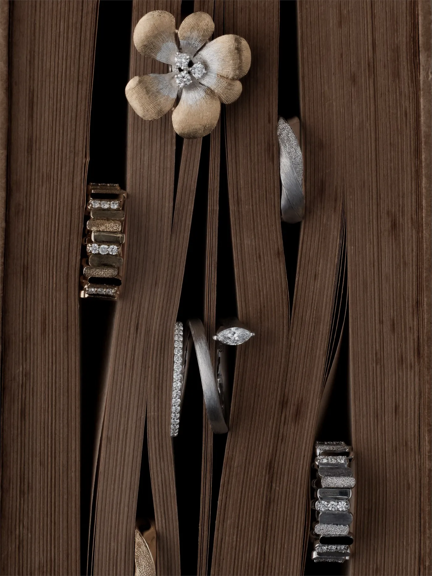 ARCELF jewelry arranged among brown threads that evoke a loom’s warp